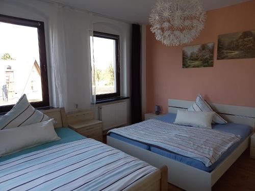 sypialnia z 2 łóżkami i żyrandolem oraz 2 oknami w obiekcie Familienfreundliche Ferienwohnung Erzgebirge w mieście Schneeberg