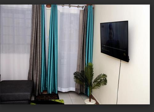 a living room with a television on a wall at Jiji Homes 1 Bedroom house with Wi-Fi king size bed. Free parking in Naivasha