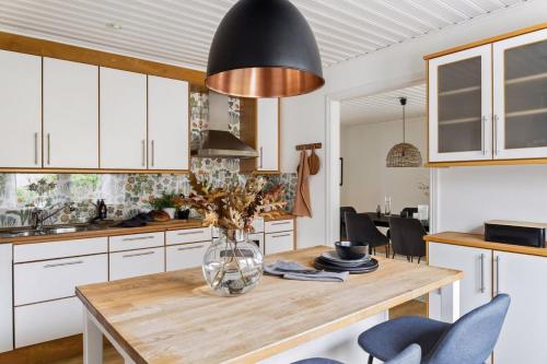 a kitchen with a wooden table with a vase of flowers at Spacious House near Sea - Delightful shelted garden in Varberg