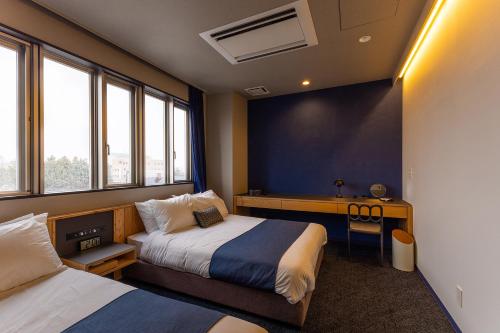 1 dormitorio con 2 camas, escritorio y ventanas en UUHOME, en Biei