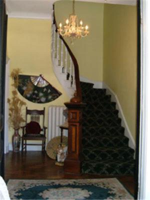 a living room with a staircase and a chandelier at Fair Street Guest House in Newport