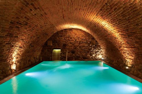 a swimming pool in a brick tunnel with blue water at Zespół Pałacowy Pacółtowo na wyłączność in Pacółtowo