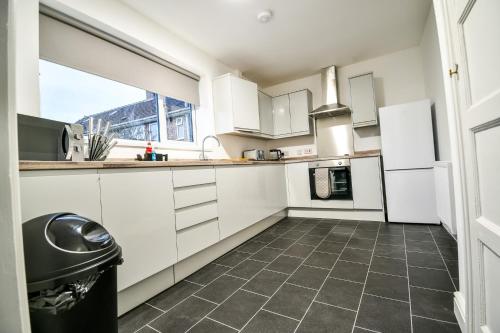 a kitchen with white cabinets and a tile floor at Dalkeith House By Horizon Stays in Hartlepool
