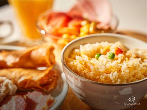 a bowl of rice on a table with a plate of food at Daiwa Roynet Hotel Kawasaki in Kawasaki