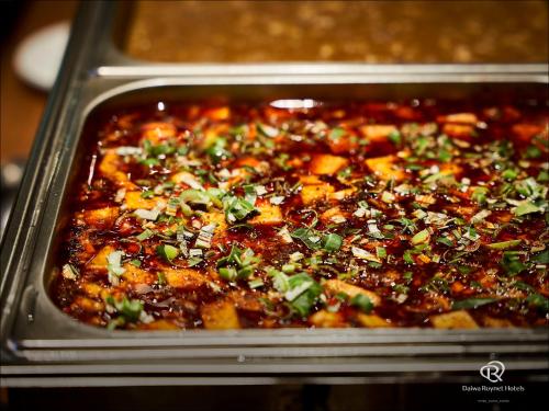 a dish of food in a pan with herbs at Daiwa Roynet Hotel Kawasaki in Kawasaki