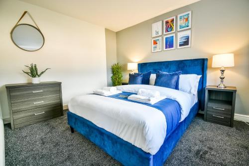 a bedroom with a blue bed and a mirror at Dalkeith House By Horizon Stays in Hartlepool
