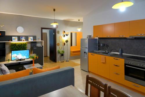 kuchnia i salon z pomarańczowymi szafkami i niebieską kanapą w obiekcie Aglaya 2 w mieście Pomorie