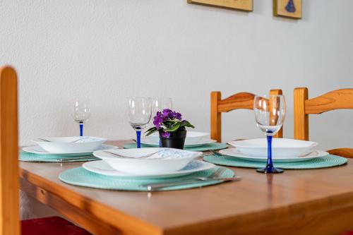 een houten tafel met borden en wijnglazen erop bij Ático Céntrico San Julian in Torrevieja