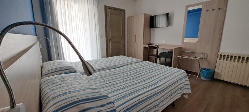 een slaapkamer met een bed met een gestreepte deken bij Hotel Splendor in Grado