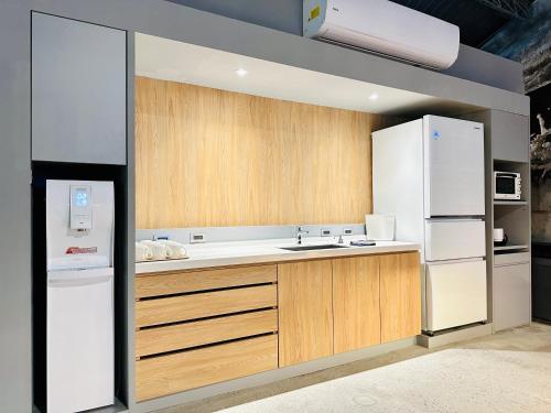 una cucina con mobili in legno e un frigorifero bianco di KW2 Hostel a Kaohsiung