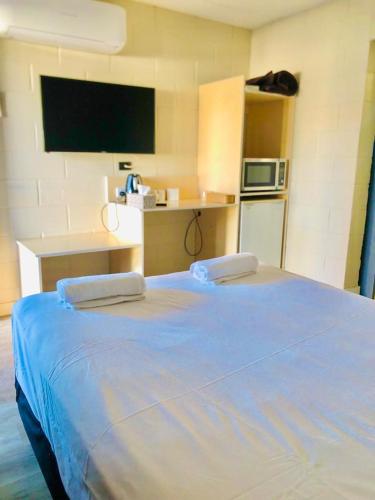 Schlafzimmer mit einem großen blauen Bett und einem TV in der Unterkunft OXFORD HOTEL MOTEL in Cunnamulla