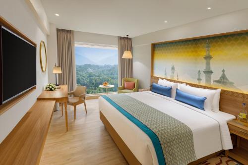 a hotel room with a bed and a flat screen tv at Bellevue Sarovar Premiere Junagadh in Junagadh