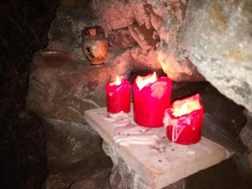 three red candles sitting on a table in a stone fireplace at Convivio Etrusco in Bassano in Teverina