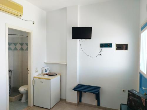 ein Bad mit WC und ein TV an der Wand in der Unterkunft Aigaio studios & rooms in Azolimnos