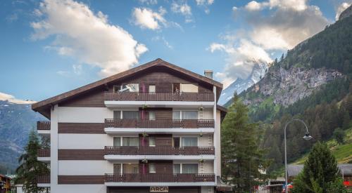 ein Gebäude mit Balkonen und einem Berg in der Unterkunft Hotel Arca Solebad & Spa in Zermatt