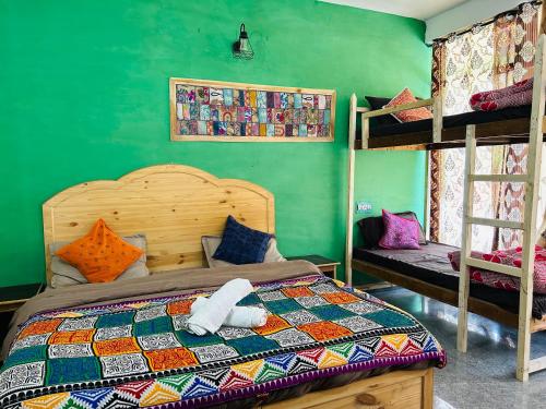 1 dormitorio con cama y pared verde en Kasol Hostel en Kasol