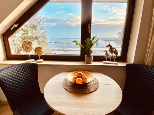 a table with a bowl of oranges on it in front of a window at gemütliche Ferienwohnungen direkt am Goitzschesee, Platz für die ganze Familie, Haustiere sind Willkommen in Große Mühle