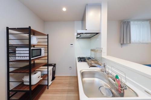 a kitchen with a sink and a microwave at Higashi Komagata House by Tranova in Tokyo