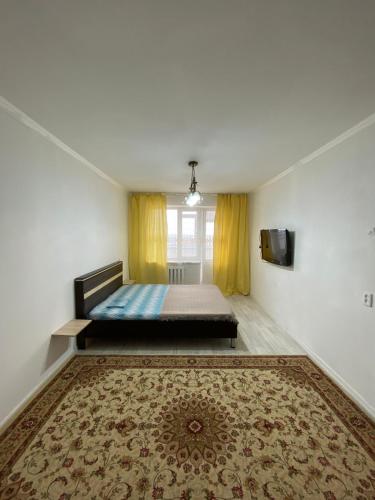 a bedroom with a bed and a rug on the floor at Уютные апартаменты в 11 микрорайоне (центр города) in Aktobe