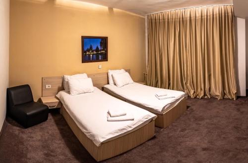 a hotel room with two beds and a chair at Hotel Beograd Struga in Struga