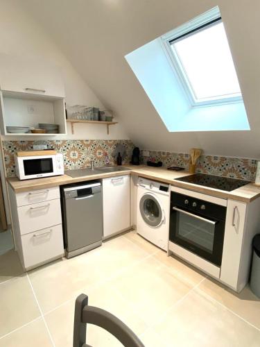 eine Küche mit einer Waschmaschine, einem Backofen und einem Fenster in der Unterkunft La Rose des Vents in Saint-Lunaire