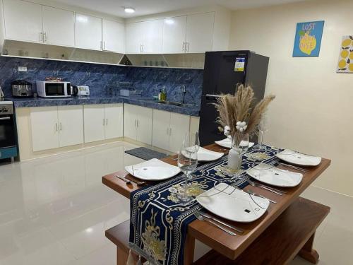 una cocina con una mesa con platos y copas de vino en 4 Bedroom Bungalow, Angeles City, en Ángeles