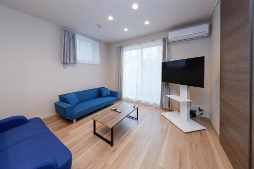 a living room with a blue couch and a tv at Higashi Komagata House by Tranova in Tokyo