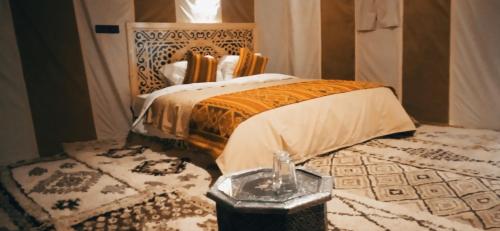 a bedroom with a bed in a room with a rug at Désert Man luxury Camp in Merzouga