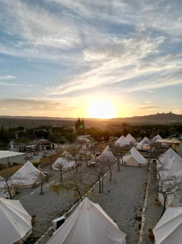 un groupe de tentes avec le coucher du soleil en arrière-plan dans l'établissement KARMEI NEGEV - מתחם גלמפינג ואטרקציות מבית גלובל גלמפינג, à Mitzpe Ramon