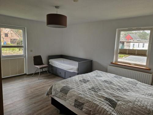 a bedroom with a bed and a chair and two windows at Ferienwohnung Ostseebad Karlshagen in Karlshagen
