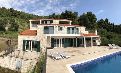 une maison avec une piscine en face d'une maison dans l'établissement Magnificent new Villa Tofta on Lopud, Croatia. Sea views from the infinity pool, à Lopud