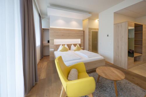 a bedroom with a bed and a yellow chair at PM-PremiumAPART Strassgang in Graz