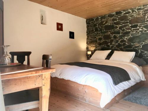 1 dormitorio con cama y pared de piedra en Le 30, en Troistorrents
