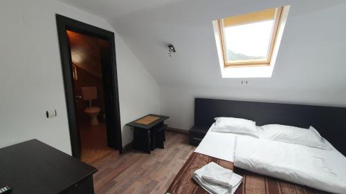 a bedroom with a bed and a table and a window at Pensiunea Paula in Moieciu de Sus