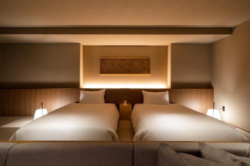 two beds sitting next to each other in a room at Atarayo Nishiizu Onsen in Izu