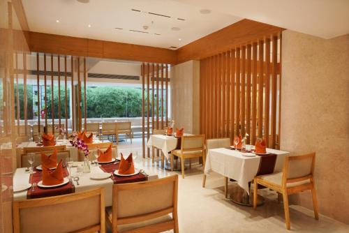 a restaurant with tables and chairs and a large window at Cocoon Hotel in Pune