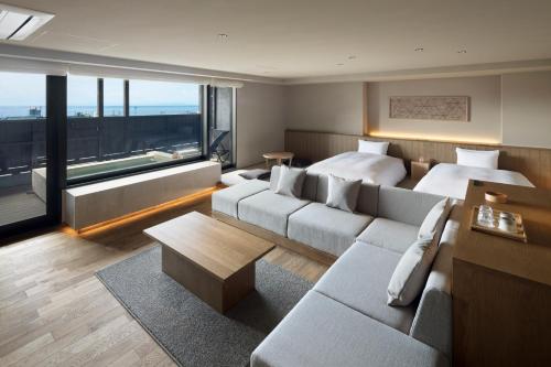 a room with two beds and a living room with a couch at Atarayo Nishiizu Onsen in Izu