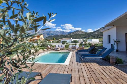 um deque com cadeiras e uma piscina numa casa em Villa avec piscine bbq pétanque Calme à 5km de la plage de sable de Calvi em Calenzana