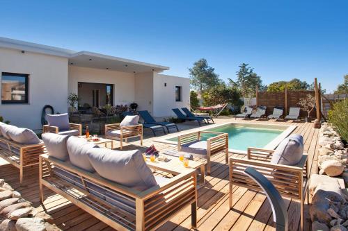 a patio with chairs and a pool and a house at Villa avec piscine bbq pétanque Calme à 5km de la plage de sable de Calvi in Calenzana