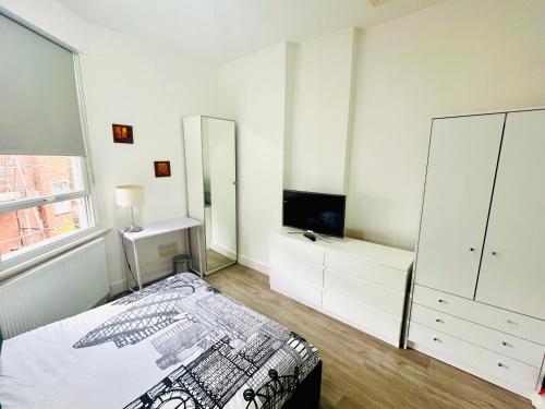 a white bedroom with a bed and a mirror at Cozy apartment in Hampstead Heat in London
