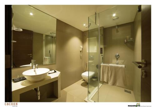 y baño con lavabo, aseo y ducha. en Cocoon Hotel en Pune