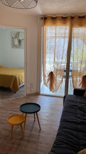un salon avec un canapé, une table et un lit dans l'établissement T2 tout équipé floralie 2, au Grau-du-Roi