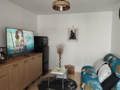 ein Wohnzimmer mit einem Sofa und einem Flachbild-TV in der Unterkunft Charmante dépendance 10 mn à pieds plage, commerces in Berck-sur-Mer