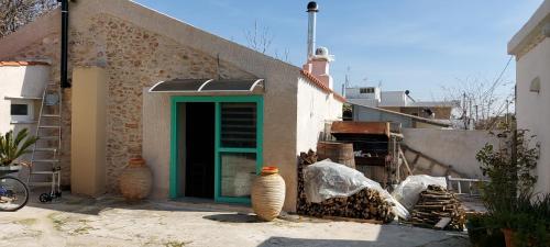 a building with a green door and two vases at Old winery in Spata