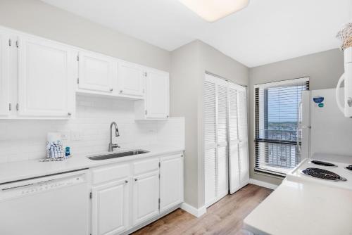 a white kitchen with white cabinets and a window at Mainsail 176 in Destin