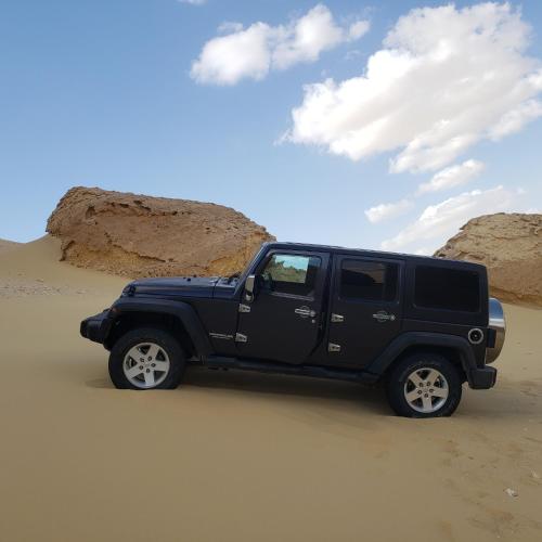 Un camión negro estacionado en la arena en el desierto en Samuel Dunes, en ‘Izbat Būrīsh al Gharbīyāh