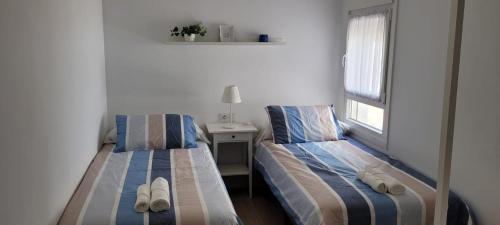 - 2 lits dans une chambre avec une table et une fenêtre dans l'établissement APARTAMENTOS IGLESIA DE SANTIAGo II, à Jerez de la Frontera