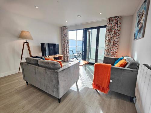 a living room with two couches and a television at 8 Putsborough - Luxury Apartment at Byron Woolacombe, only 4 minute walk to Woolacombe Beach! in Woolacombe