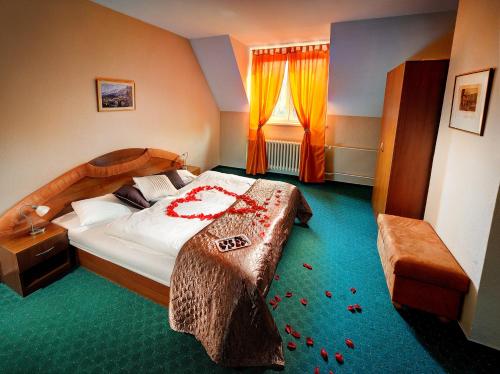 a bedroom with a large bed with red flowers on it at Penzión Kamzik in Stará Lesná