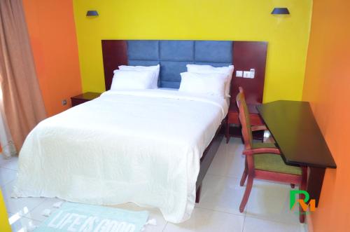 a bedroom with a large bed and a desk and a table and chair at RESIDENCES MICKEL in Yaoundé